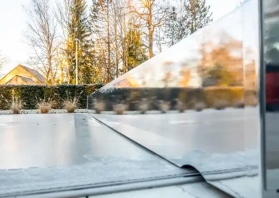 Surface de piscine couverte avec une structure métallique réfléchissante, entourée de végétation et d'arbres en arrière-plan sous un ciel dégagé.