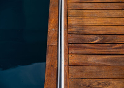 Gros plan sur le rail intégré dans la terrasse en bois pour le système de couverture de piscine.