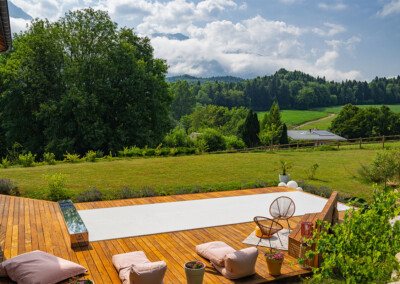Piscine recouverte du modèle automatique de la Coverseal entourée d’une terrasse en bois et offrant une vue sur les montagnes et la campagne.