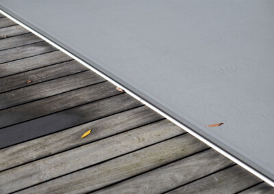 Gros plan sur la finition de la couverture Coverseal grise intégrée dans une terrasse en bois.